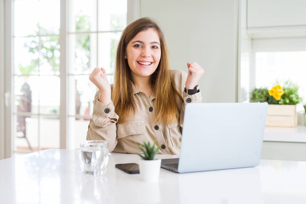 Красива молода жінка за допомогою комп'ютерного ноутбука кричить гордо і святкує перемогу і успіх дуже схвильовані, веселі емоції
 - Фото, зображення
