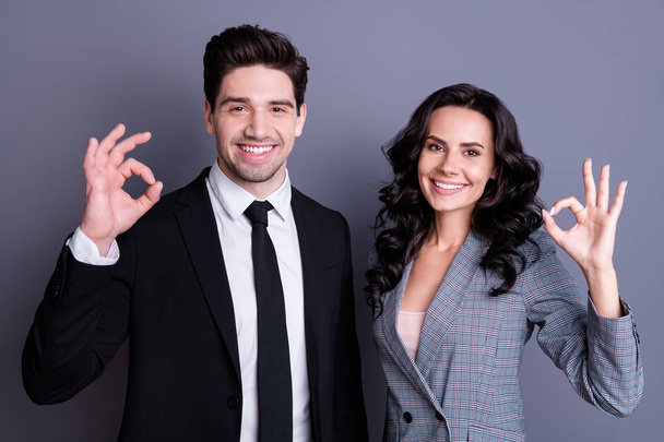 Portrait of beautiful two bussinesspeople showing ok sign wearing stylish black jacket blazer tie isolated over gray background - Photo, Image