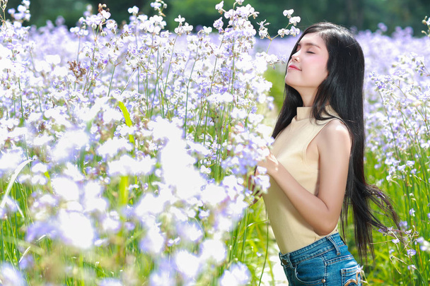 portret pięknej kobiety o szczęśliwym czasie i ciesząc się wśród kwiatów Naga-Crested pola w przyrodzie - Zdjęcie, obraz