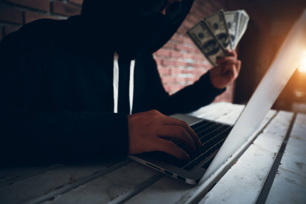 хакер пытается взломать и украсть данные информационной системы с компьютера и показать деньги после взлома
 - Фото, изображение