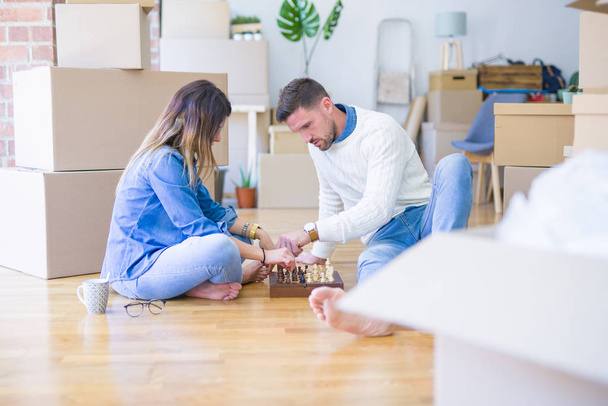 Giovane bella coppia che gioca a scacchi nella nuova casa intorno scatole di cartone
 - Foto, immagini