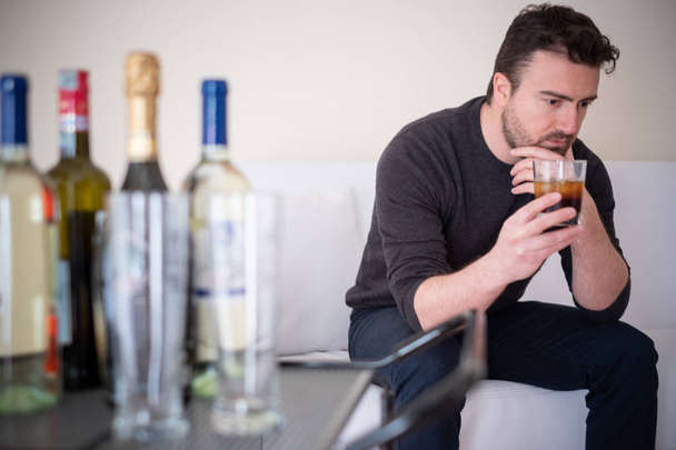 Uomo depresso che beve alcolici a casa
 - Foto, immagini