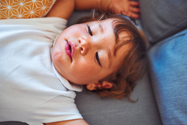 Gyönyörű kisgyermek kislány visel fehér Body fekve a kanapén - Fotó, kép