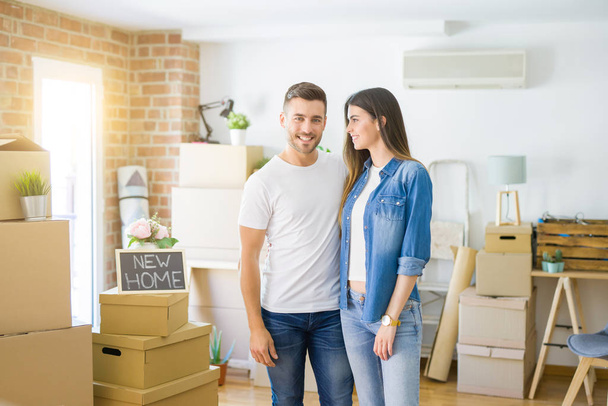 Beautiful young couple moving to a new house, smiling happy arround cardboard boxes - Photo, Image