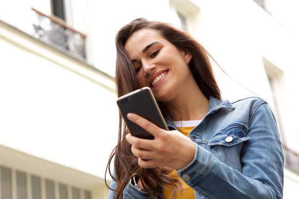 Крупним планом портрет щасливої молодої жінки дивиться на мобільний телефон
 - Фото, зображення