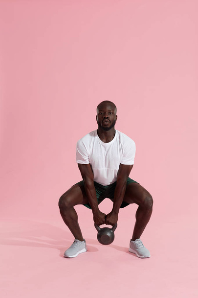 Fitness training. Sports man doing kettlebell squat workout - Fotó, kép
