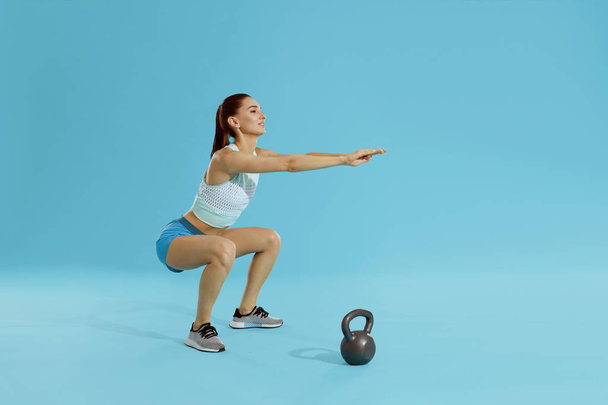 Squats. Fitness woman in sports wear exercising, doing squat  - Fotó, kép