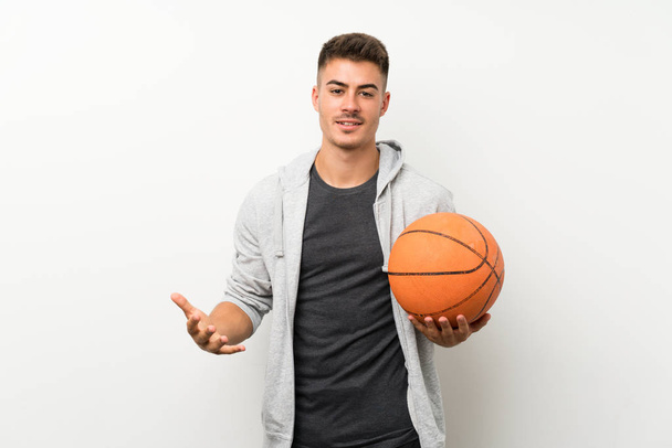 Спортсмен над ізольованою білою стіною з м'ячем баскетболу
 - Фото, зображення