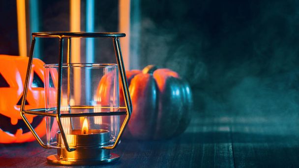 Halloween concept, spooky decorations with lighting up candle and candle holder with green tone smoke around on a dark wooden table, close up. - Photo, image