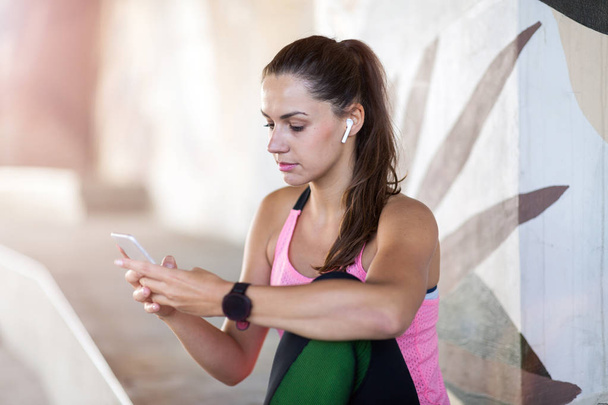 Female runner using smartphone in a urban city area - Zdjęcie, obraz