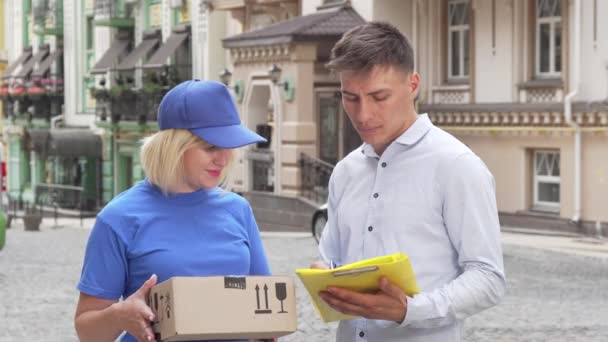 Knappe jonge man ondertekenen papers ontvangen van een pakket van levering vrouw - Video