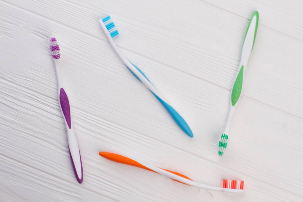 Colored tooth brushes on white wooden background. - Foto, Imagen