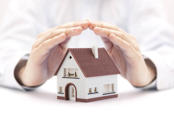 Property insurance concept. House miniature protected by hands. - Zdjęcie, obraz