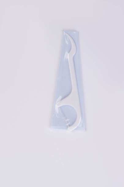 White dental floss pick on white background. - Photo, Image