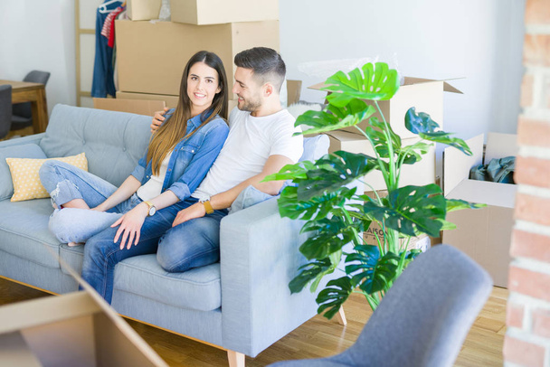 Молода пара закохалася, розслабляючись, сидячи на дивані в новому будинку, посміхаючись щаслива за переїзд в нову квартиру
 - Фото, зображення