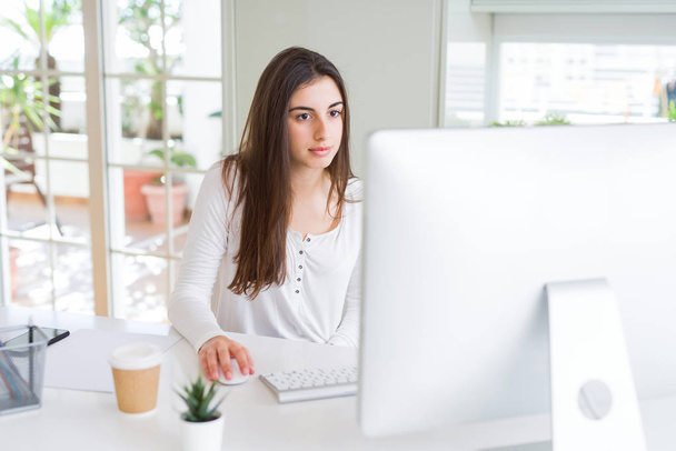 Gyönyörű fiatal üzleti nő dolgozik számítógéppel, mosolyogva - Fotó, kép