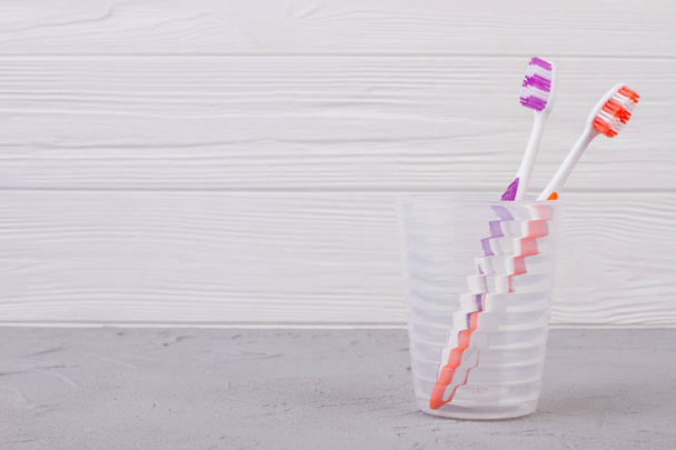 Πολύχρωμη οδοντόβουρτσα σε γυαλί σε ξύλινο φόντο. - Φωτογραφία, εικόνα
