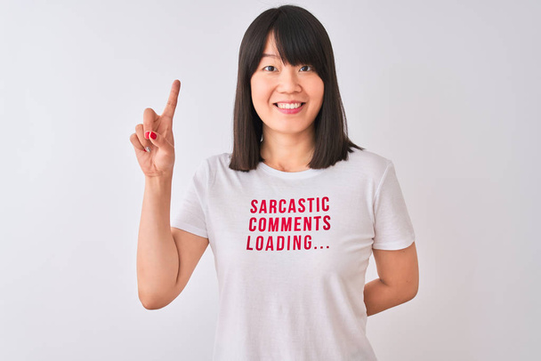 Młoda piękna Chińska kobieta ubrana w t-shirt Fanny na białym tle zaskoczony pomysłem lub pytaniem wskazującym palcem z szczęśliwą twarzą, numer jeden - Zdjęcie, obraz