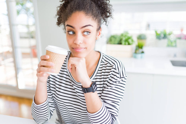Giovane ragazza afroamericana che beve un caffè su una tazza di carta da asporto faccia seria pensando alla domanda, idea molto confusa
 - Foto, immagini