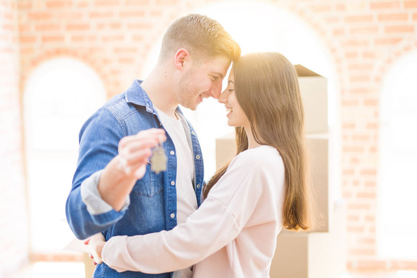Beautiful young couple hugging in love and showing keys of new h - Фото, зображення