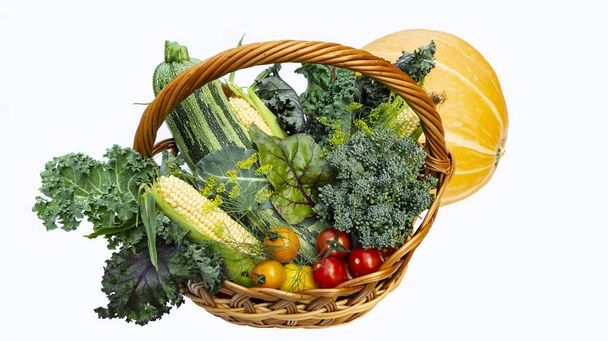 Осінні овочі в кошику ізольовані на білому тлі. Врожай кабачків, помідорів, кукурудзи, капустяної капусти та апельсинового гарбуза, брокколі поміщені в кошик
. - Фото, зображення