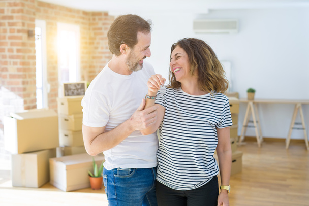 中年のシニアロマンチックなカップルは、新しい家に引っ越すために幸せに微笑む家の鍵を保持し、示しています - 写真・画像