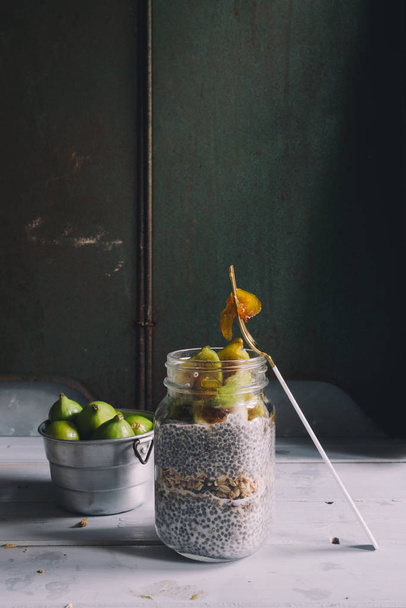 Chia seeds fig pudding on a glass mason jar, on a rustic environment and against a dark background, with figs - Φωτογραφία, εικόνα