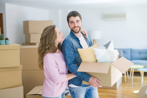 Joven hermosa pareja muy feliz juntos sosteniendo cajas de cartón moviéndose a un nuevo hogar
 - Foto, Imagen