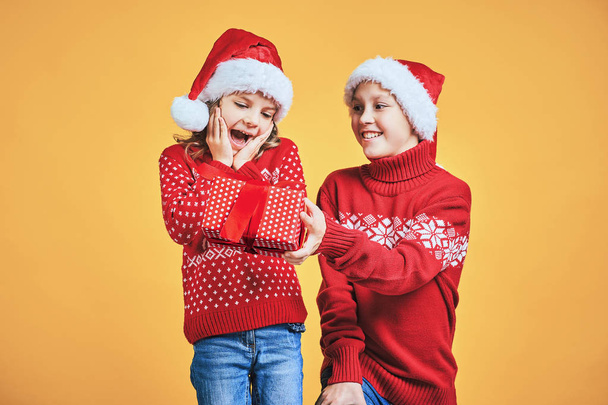Boy handing Christmas present to surprised girl - Foto, imagen