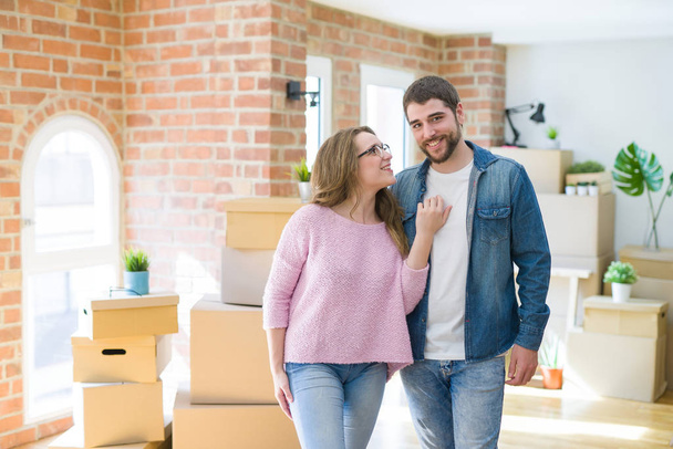 Jeune couple autour de boîtes en carton très heureux de déménager dans une nouvelle maison
 - Photo, image