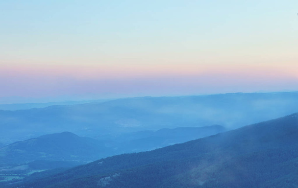 Mountain range with visible silhouettes through the evening fog. - Fotó, kép