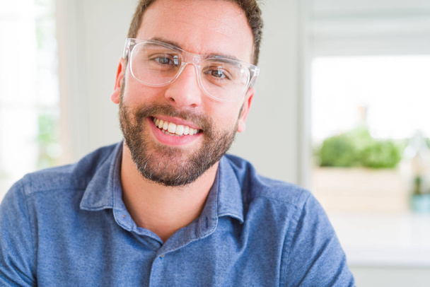Pohledný muž nosí brýle a usmívá se uvolnil na kameru - Fotografie, Obrázek