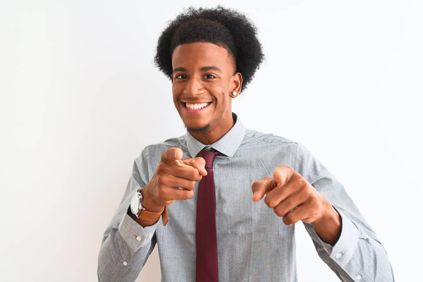 Nuori afrikkalainen liikemies solmiossa seisoo valkoisella pohjalla osoittaen sormella kameraa iloisella ja hauskalla naamalla. Hyvä energia ja vibes
. - Valokuva, kuva