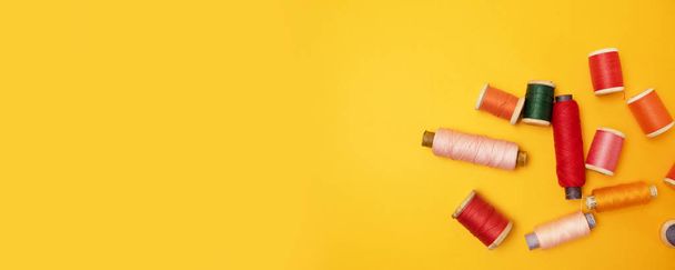 Швейные аксессуары и ткань на желтом фоне. Шитье ниток, иголок, ткани, пуговиц и сантиметров
 - Фото, изображение