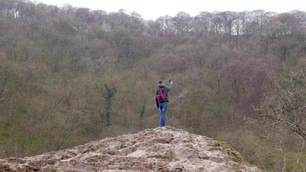 Young man standing on a rock trying to catch a signal on the mobile phone - Footage, Video