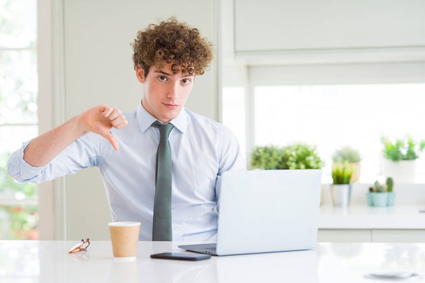 Young Business man werken met computer laptop op het kantoor met boos gezicht, negatieve teken tonen afkeer met duimen naar beneden, afwijzing concept - Foto, afbeelding