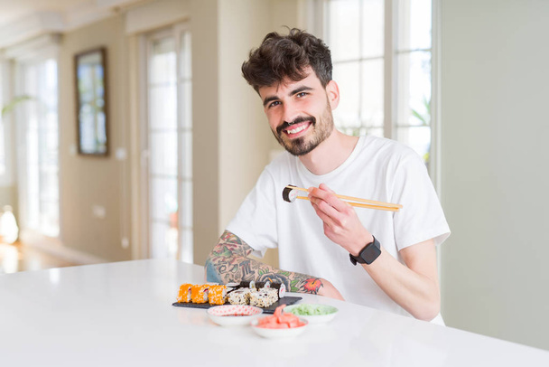 Jonge man eten sushi Aziatisch eten met behulp van choopsticks - Foto, afbeelding