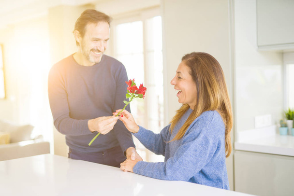 Romantic middle age couple holding flowers in love at home - Φωτογραφία, εικόνα
