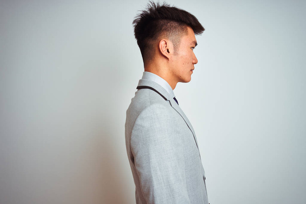Asiatique chinois homme d'affaires portant costume et cravate debout sur fond jaune isolé regardant vers le côté, pose de profil relax avec visage naturel avec sourire confiant
. - Photo, image