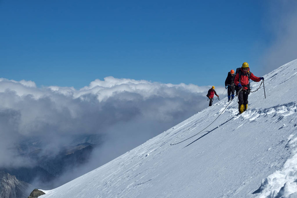 Bunch of mountaineers climbs or alpinists to the top of a snow-c - Fotografie, Obrázek