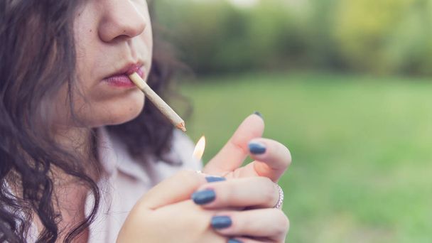 Girl smoking medical marijuana joint outdoors, close-up. Cannabi - Фото, зображення