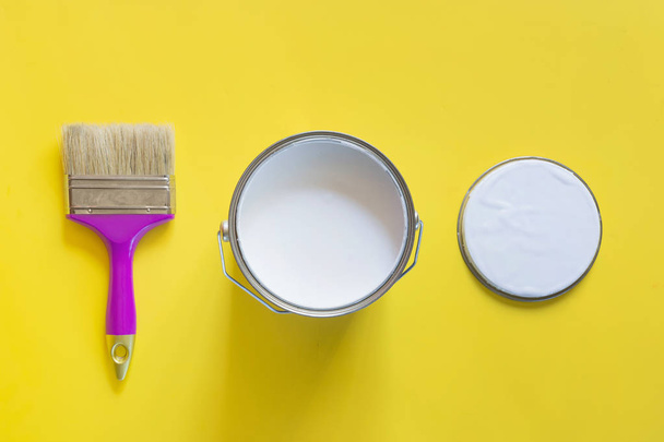 Purple brush with open can of white paint on yellow background. Trend concept. - Foto, afbeelding