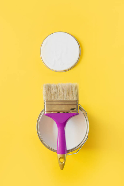 Purple brush with open can of white paint on yellow background. Trend repairs concept. - Φωτογραφία, εικόνα