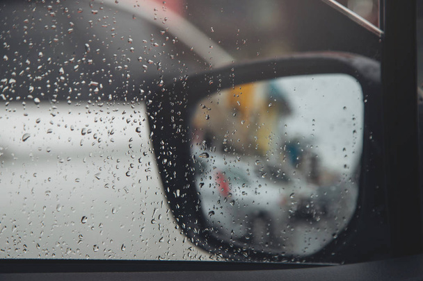 Σταγόνες βροχής στο γυάλινο παρμπρίζ μέσα στη νύχτα. δρόμο με τη βαριά βροχή. Το φανάρι του μπόκεη. Απαλή εστίαση. Παρακαλώ Οδηγήστε προσεκτικά, ολισθηρό δρόμο. Απαλή εστίαση. αυτοκίνητο μποτιλιάρισμα. - Φωτογραφία, εικόνα