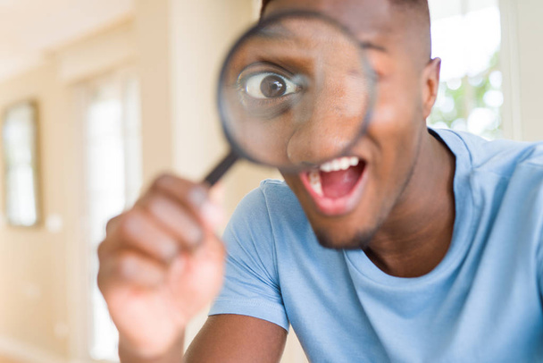 Young african man looking through magnifying glass - Foto, imagen