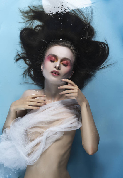 A beautiful naked girl with conceptual makeup in red tones is ly - Foto, imagen