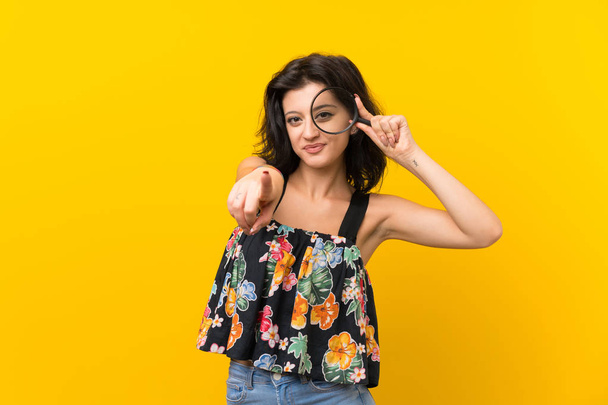Giovane donna su sfondo giallo isolato con una lente d'ingrandimento
 - Foto, immagini