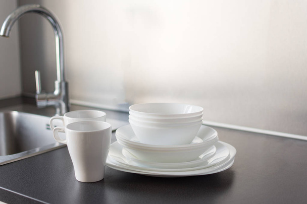 Набор свежих мытых тарелок и столовых приборов на кухонном столе
. - Фото, изображение