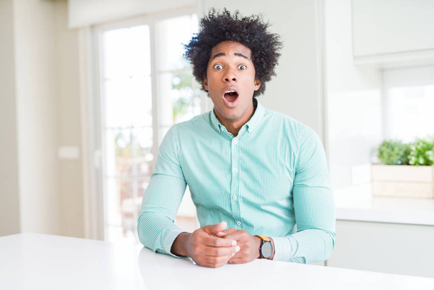Homme d'affaires afro-américain portant une chemise élégante effrayée et choquée par l'expression surprise, la peur et le visage excité
. - Photo, image