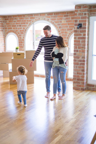 Beautiful family with a kid standing at new home around cardboard boxes - Photo, Image